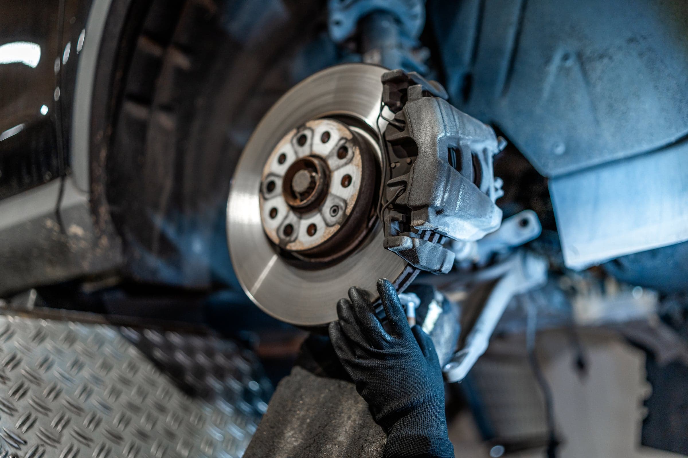 Close view of a brake rotor and caliper with the wheel removed during a safety systems inspection